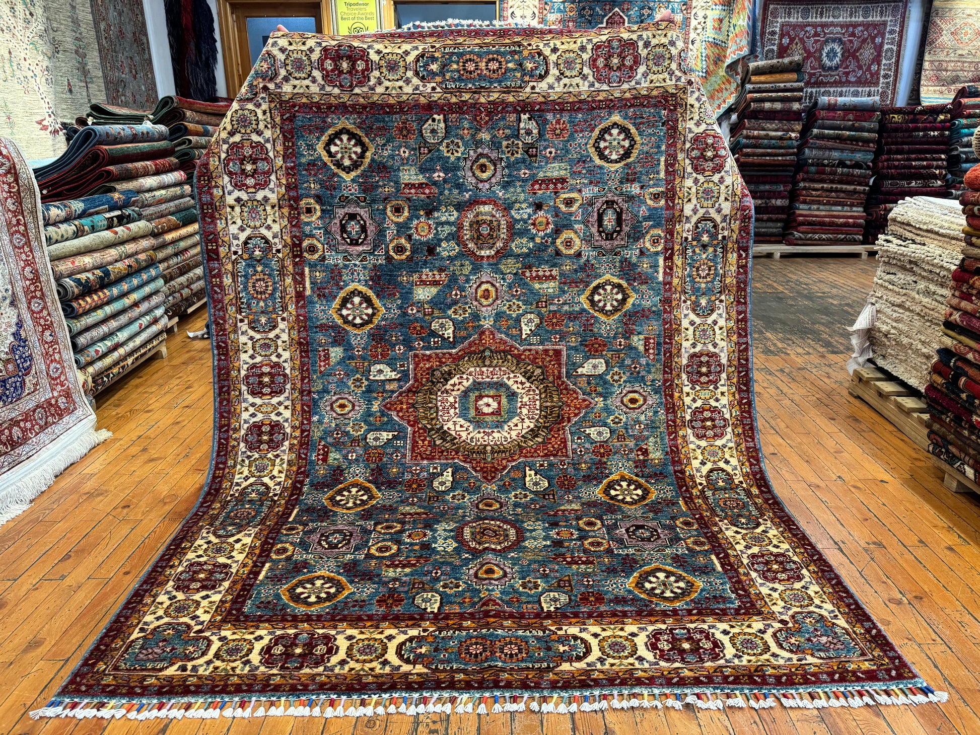 Decorative rug with intricate patterns on a wooden floor in a store setting.