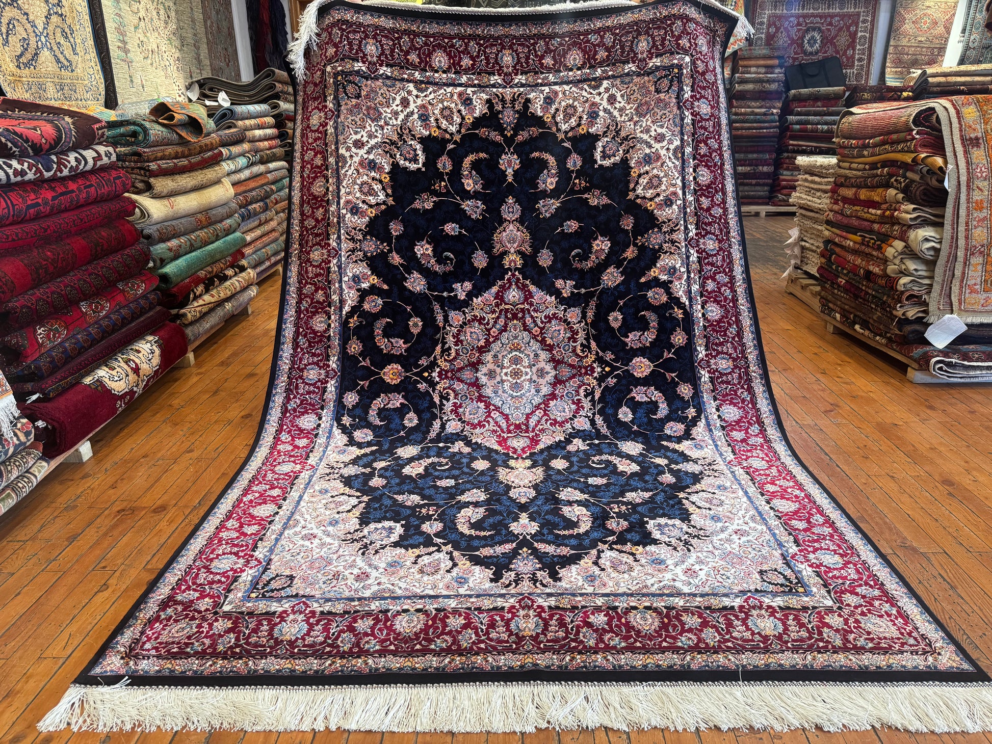 Decorative rug with intricate patterns on a wooden floor in a store setting.